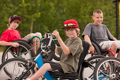 Young boys sitting in wheelchairs and a hand cycles