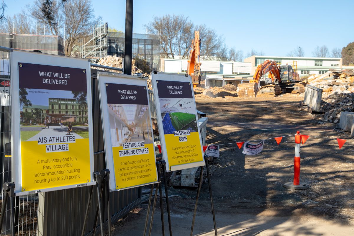 Demolition works at the AIS alongside posters of the three new world-class facilities to come