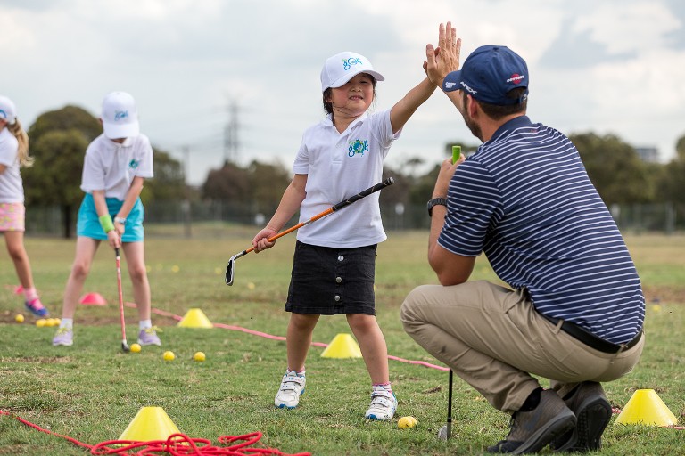 Child high fiving adult while playing golf
