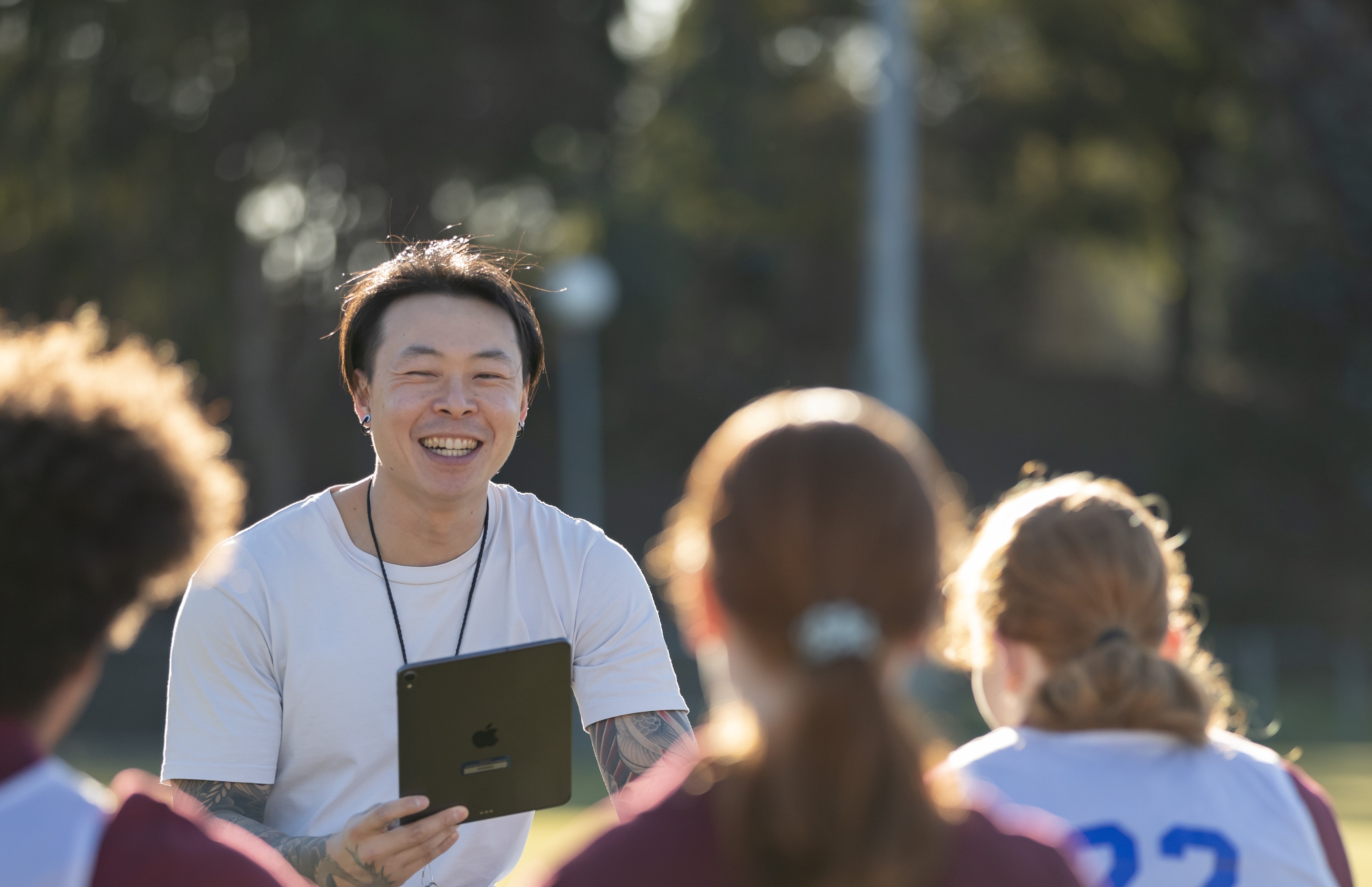 Coach with clipboard talking to people