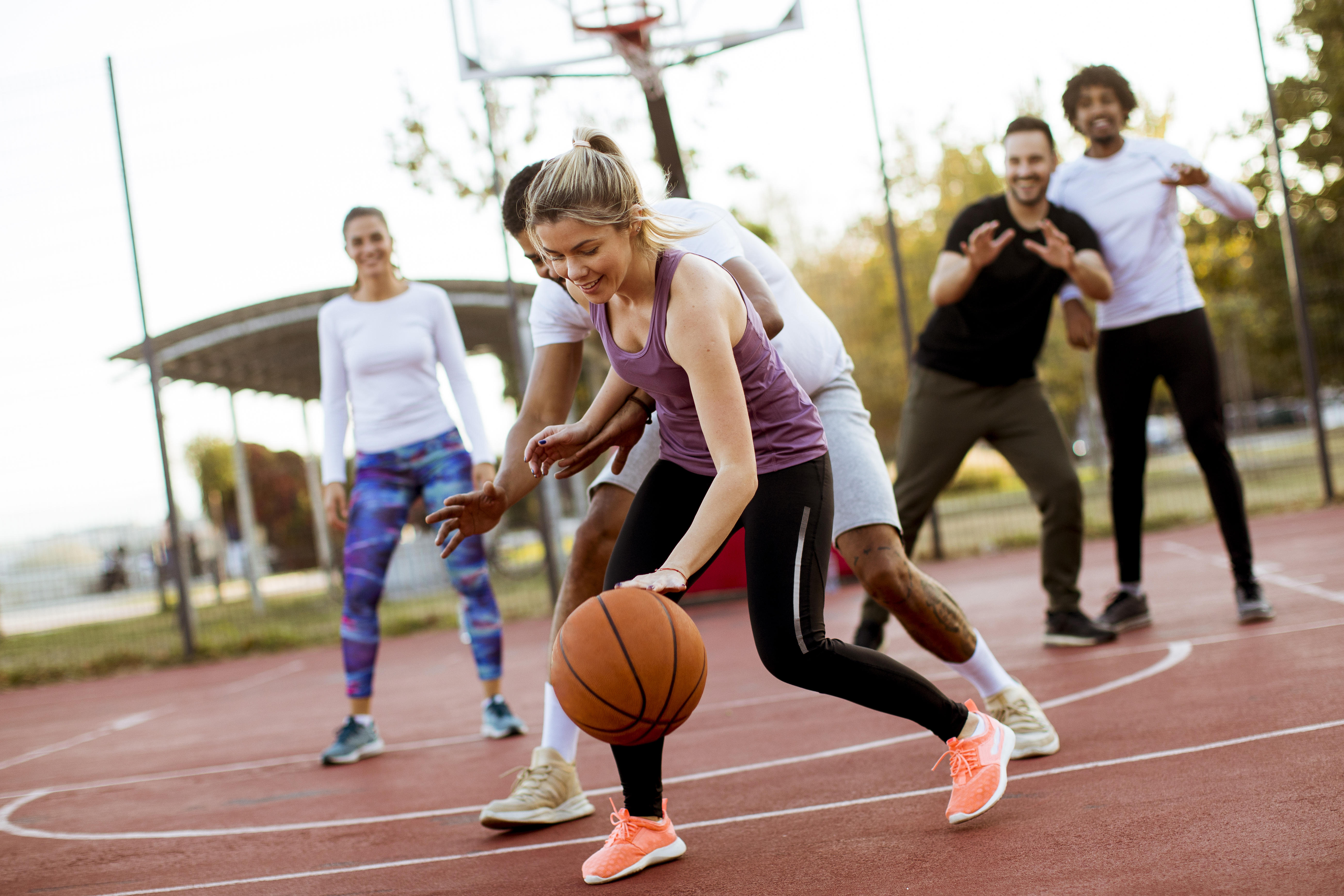 A group of five people playing a social game of basketball