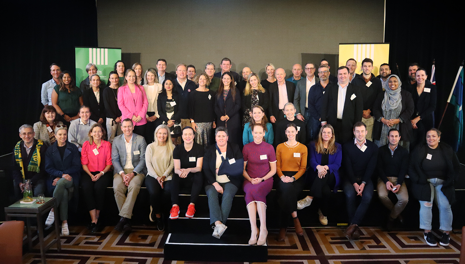 A group of people gather on stage and smile for a photo.