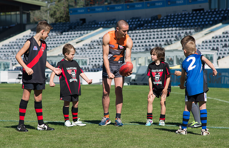 AFL player showing kids how to handball