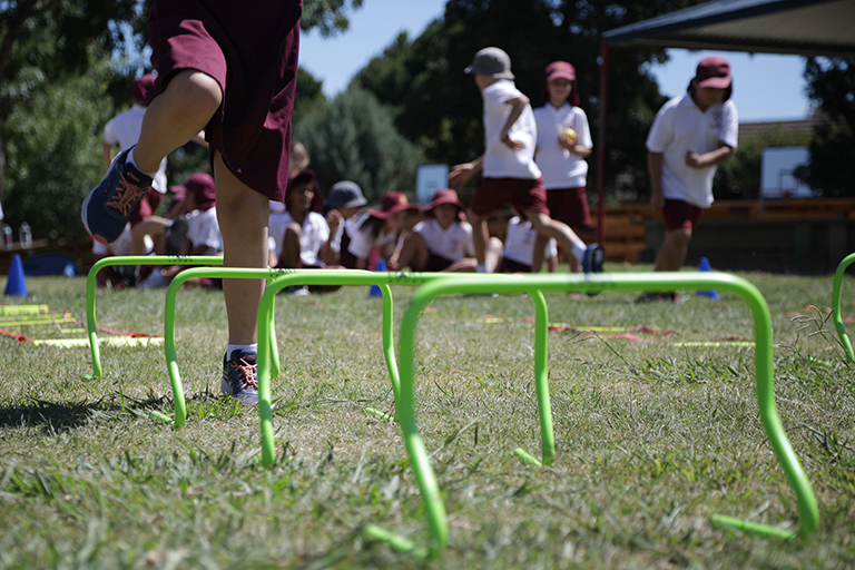 Image of a young child jumping over a hurdle.