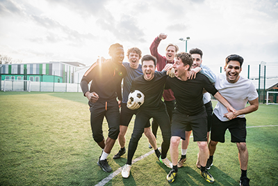 Group of young man hugging and celebrating soccer match success