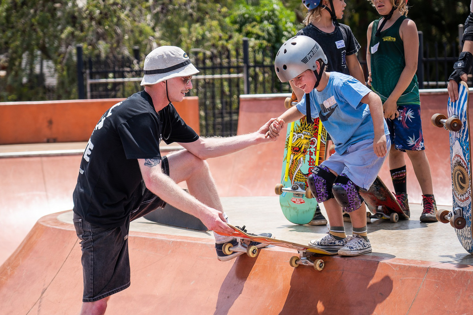 A skateboard instructor teaches a small boy prepare to "drop in" at Broome Skate Park.