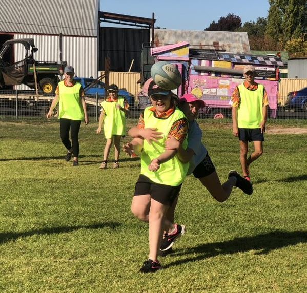 students in yellow vests playing footy