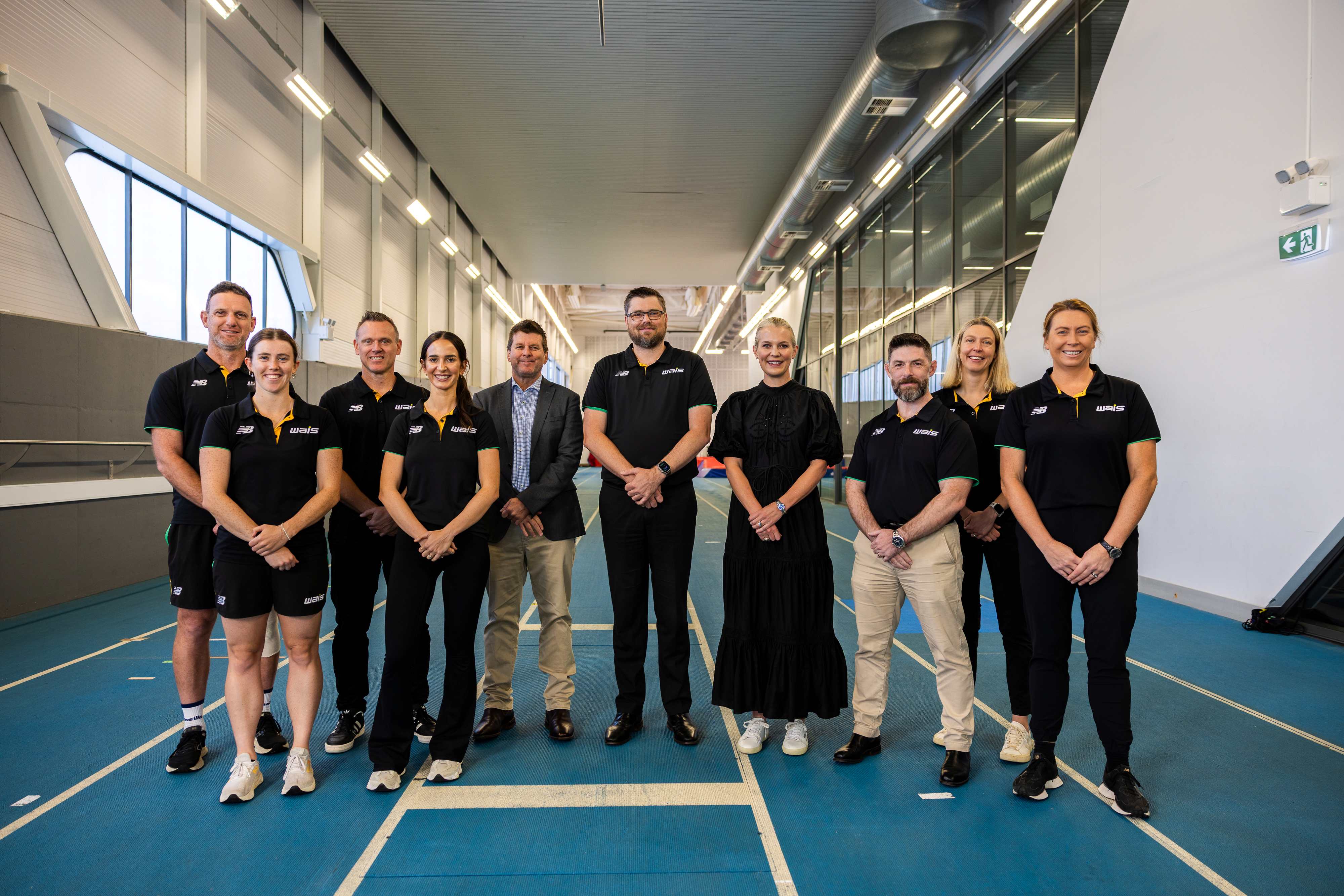 coaches and sporting leaders pose for photo on running track
