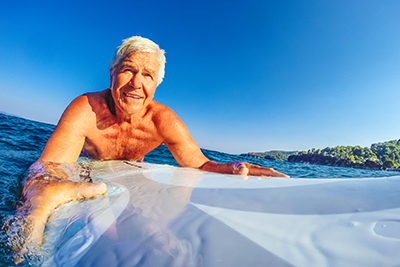 Mature age man lying on a surfboard