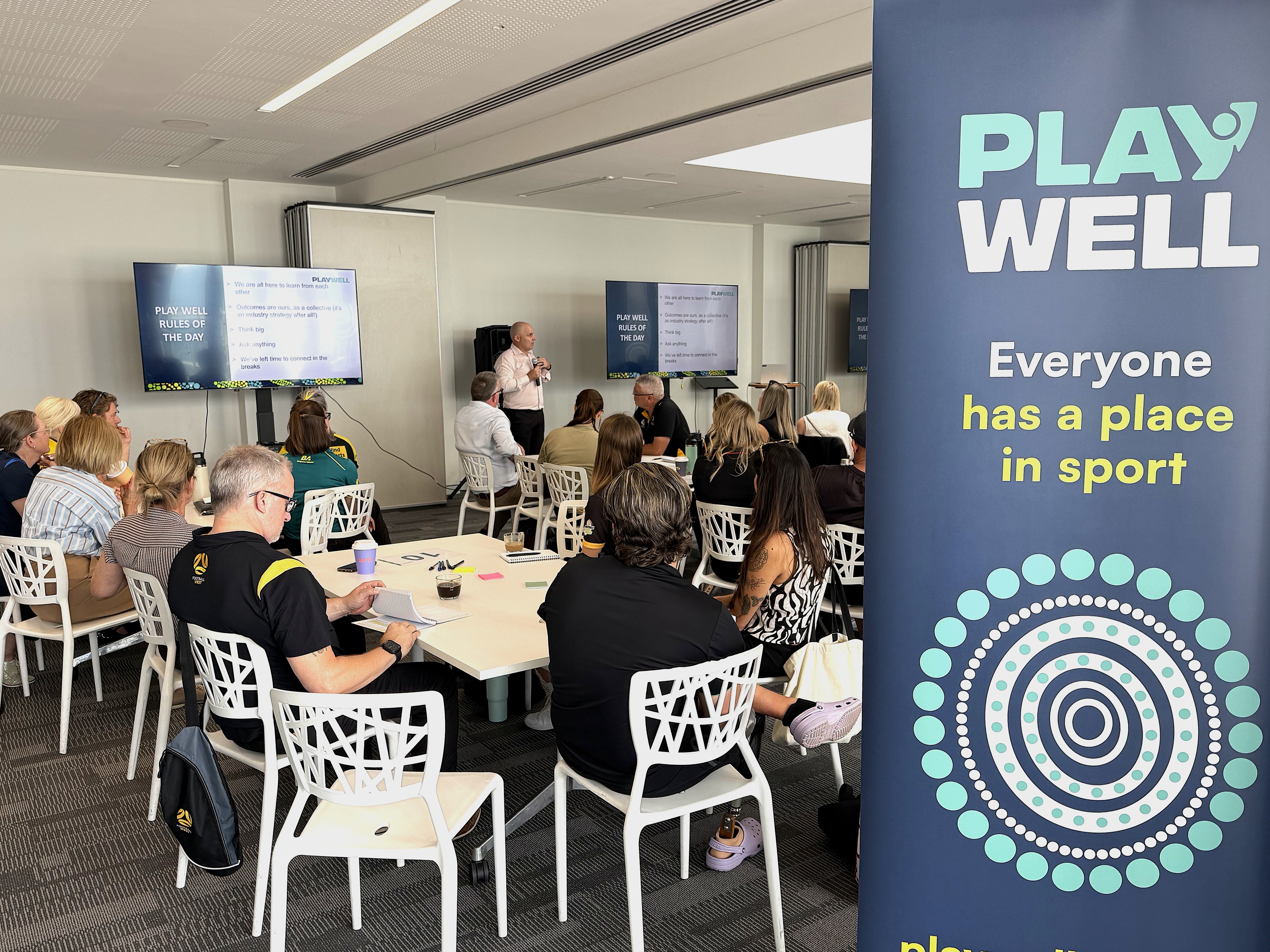 Image of people sitting and listening to a presenter speak at a conference