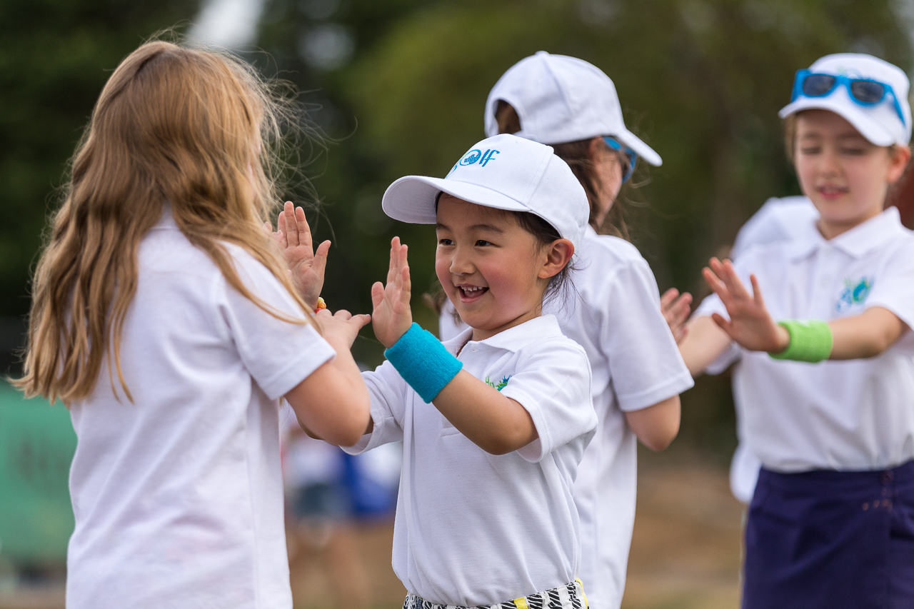 Four children giving each other high-fives during a golf Sporting Schools program.