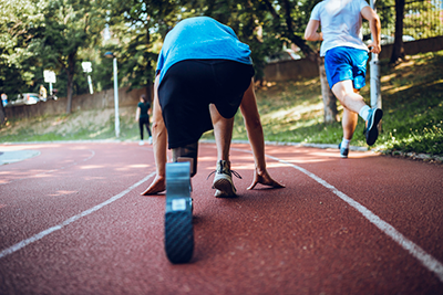 Man with prosthetic leg in a starting pose on an athletics track