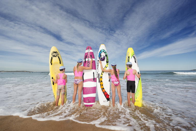 Surf life savers stand with their boards on the beach