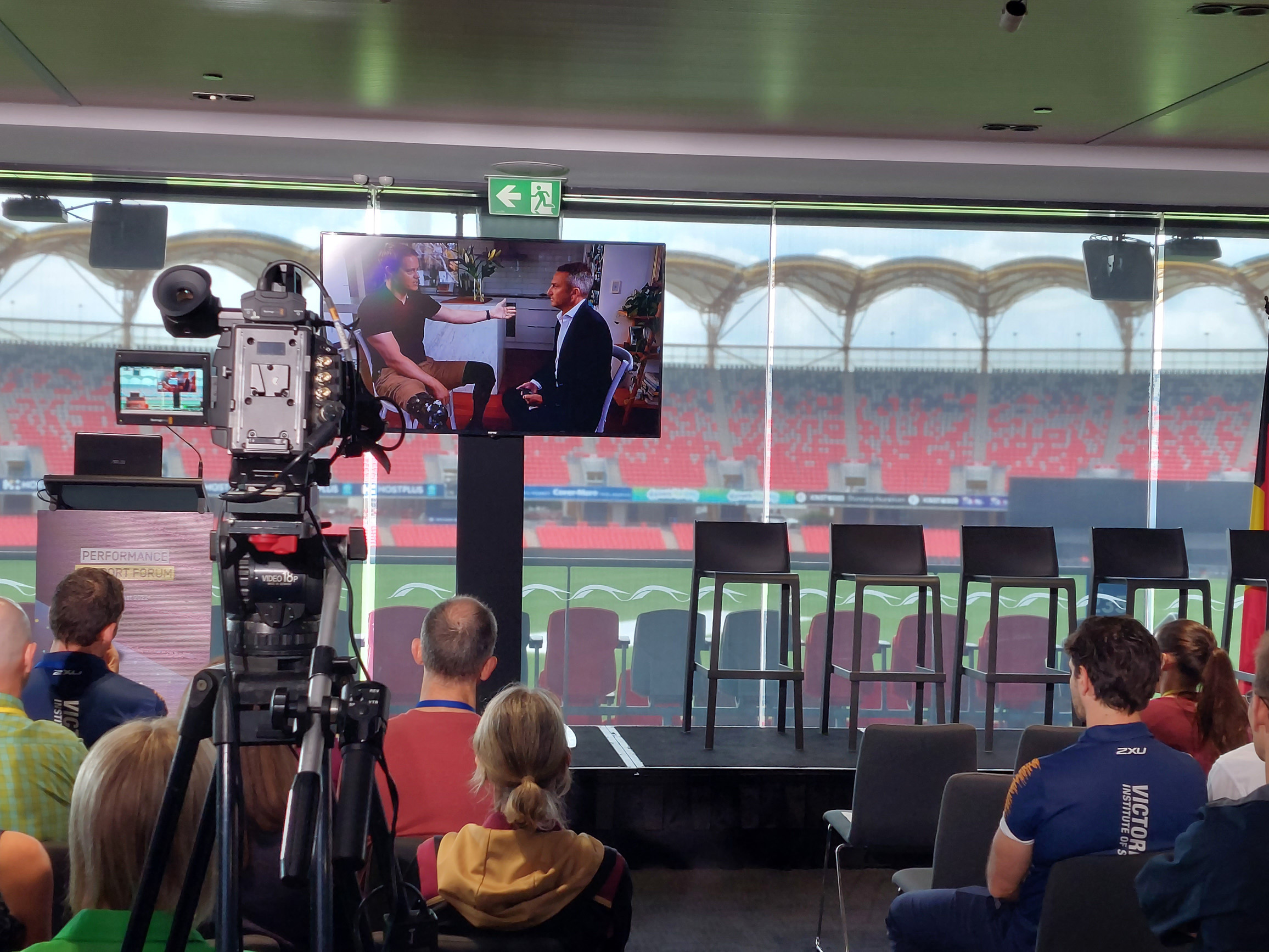 People watching a screen with Curtis McGrath talking