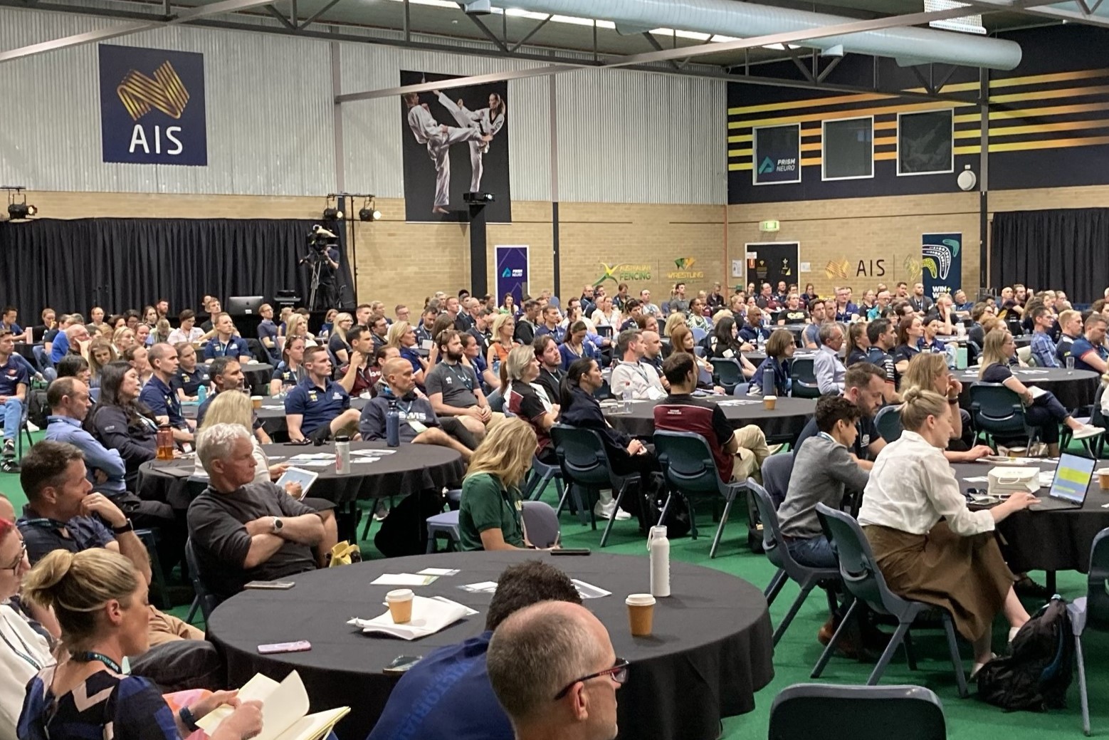 Photo of the Combat Centre at the AIS filled with tables and over 300 members of the high performance sector.