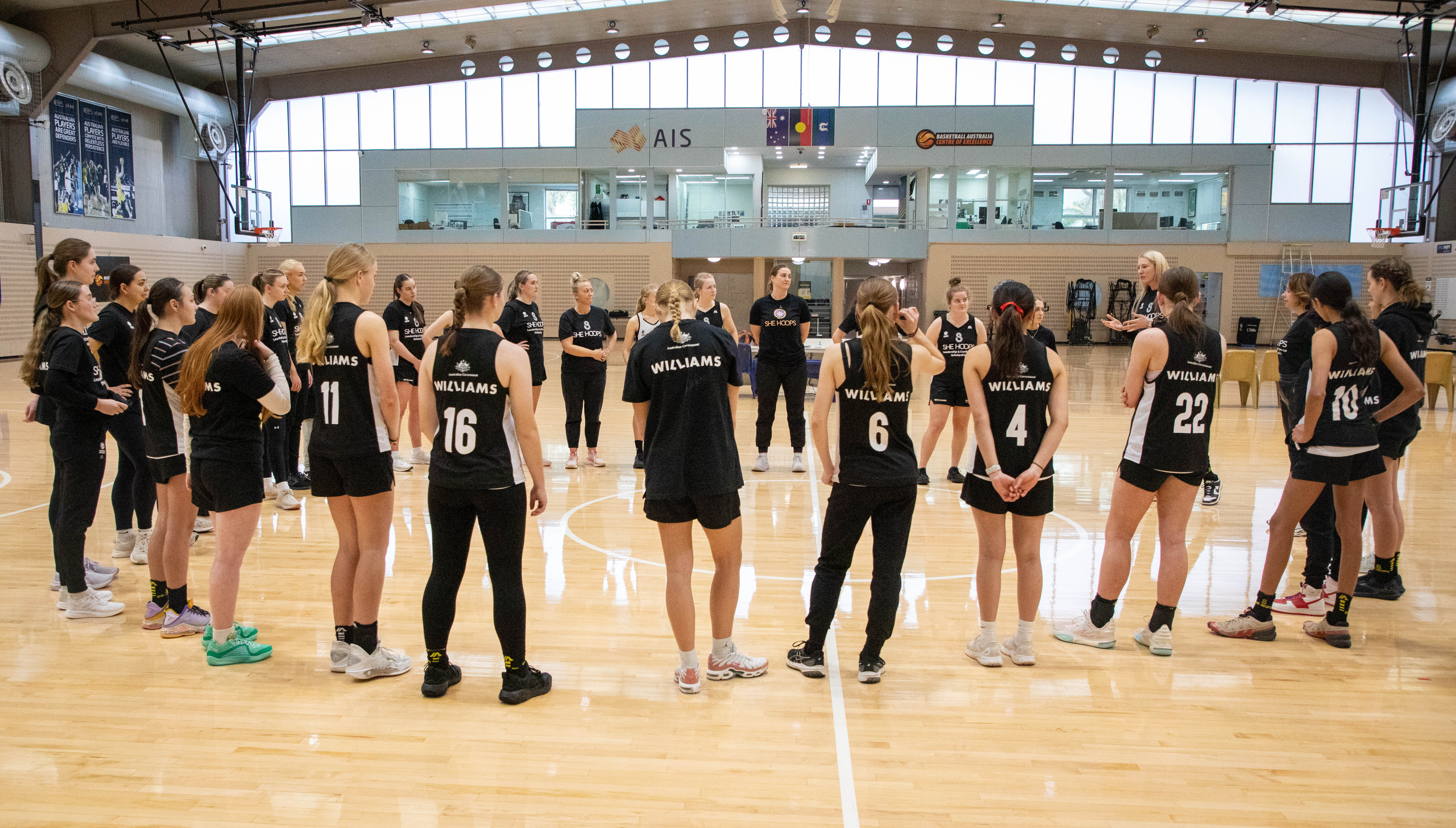 Image of scholarship recipients in a huddle on the basketball court