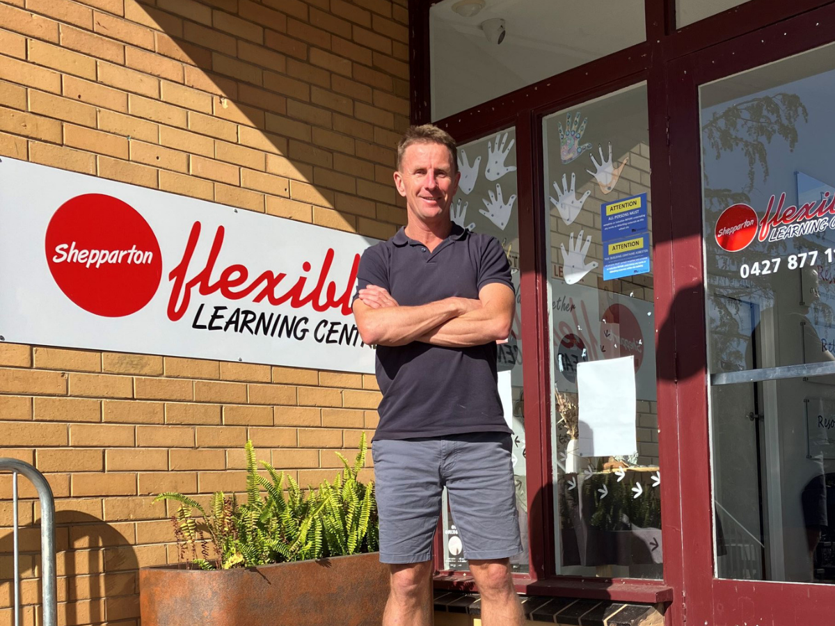 A man proudly standing in front of his school