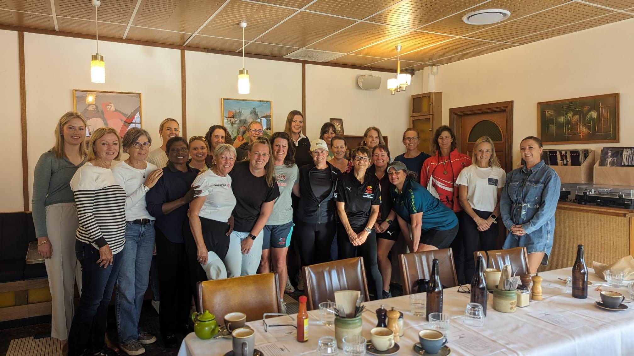 23 women stand together in a restaurant, they are all part of the Australian Athletics mentoring program, run by Dianne Huxley.