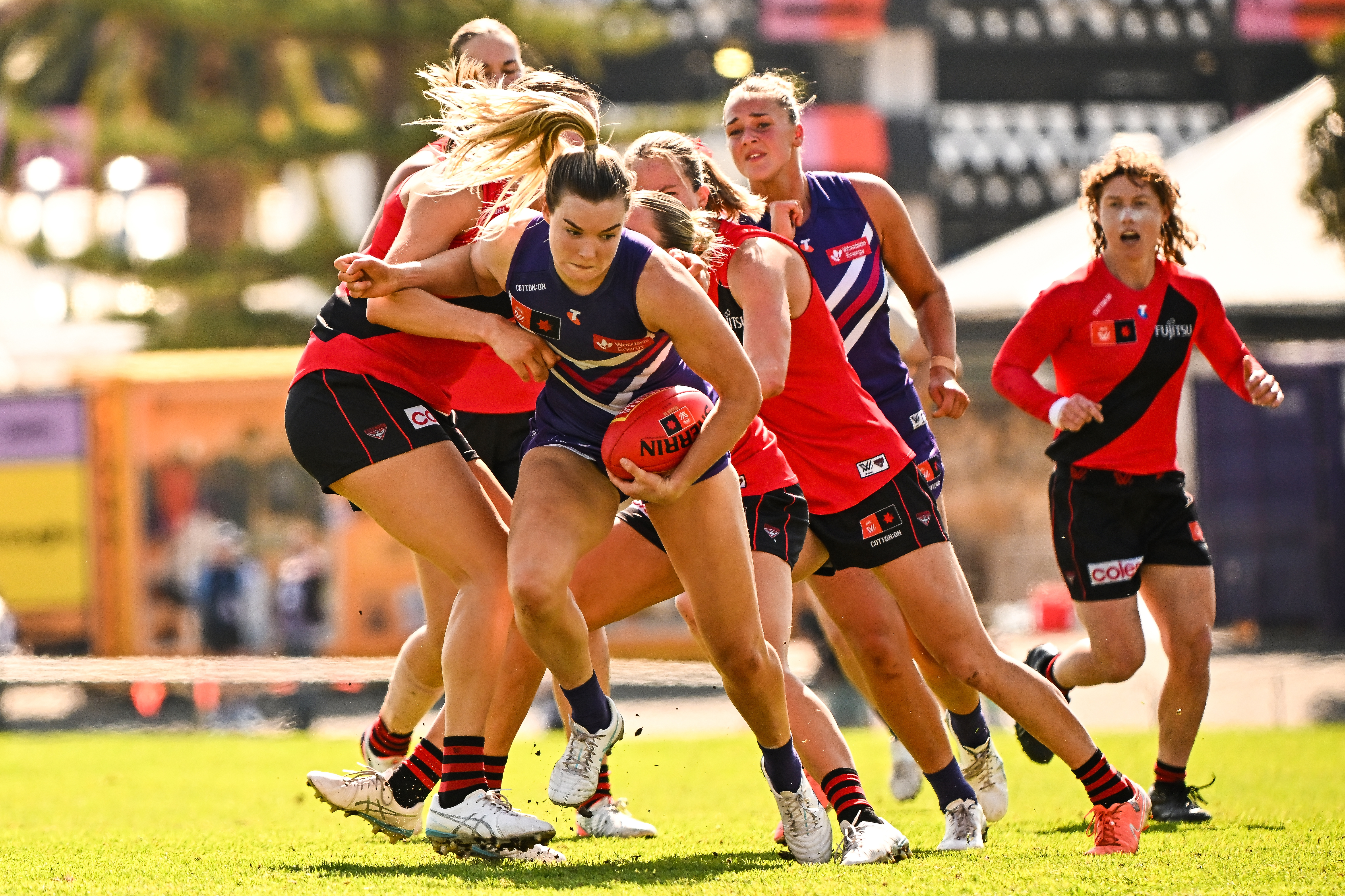 Fremantle Dockers midfielder Hayley Miller during a game pushing through a group of players while holding the ball