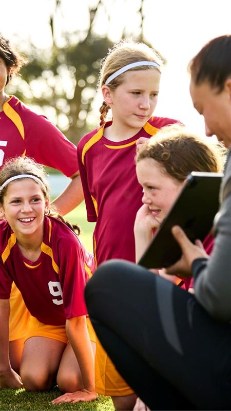 Female football coach talking to young girls