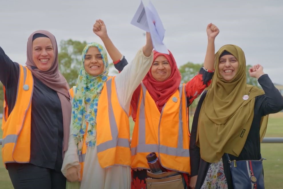 Naaz Asim, President, Northern Badminton Club with three volunteers all cheering facing the camera at Fawkner Sports Day in Fawkner in Victoria