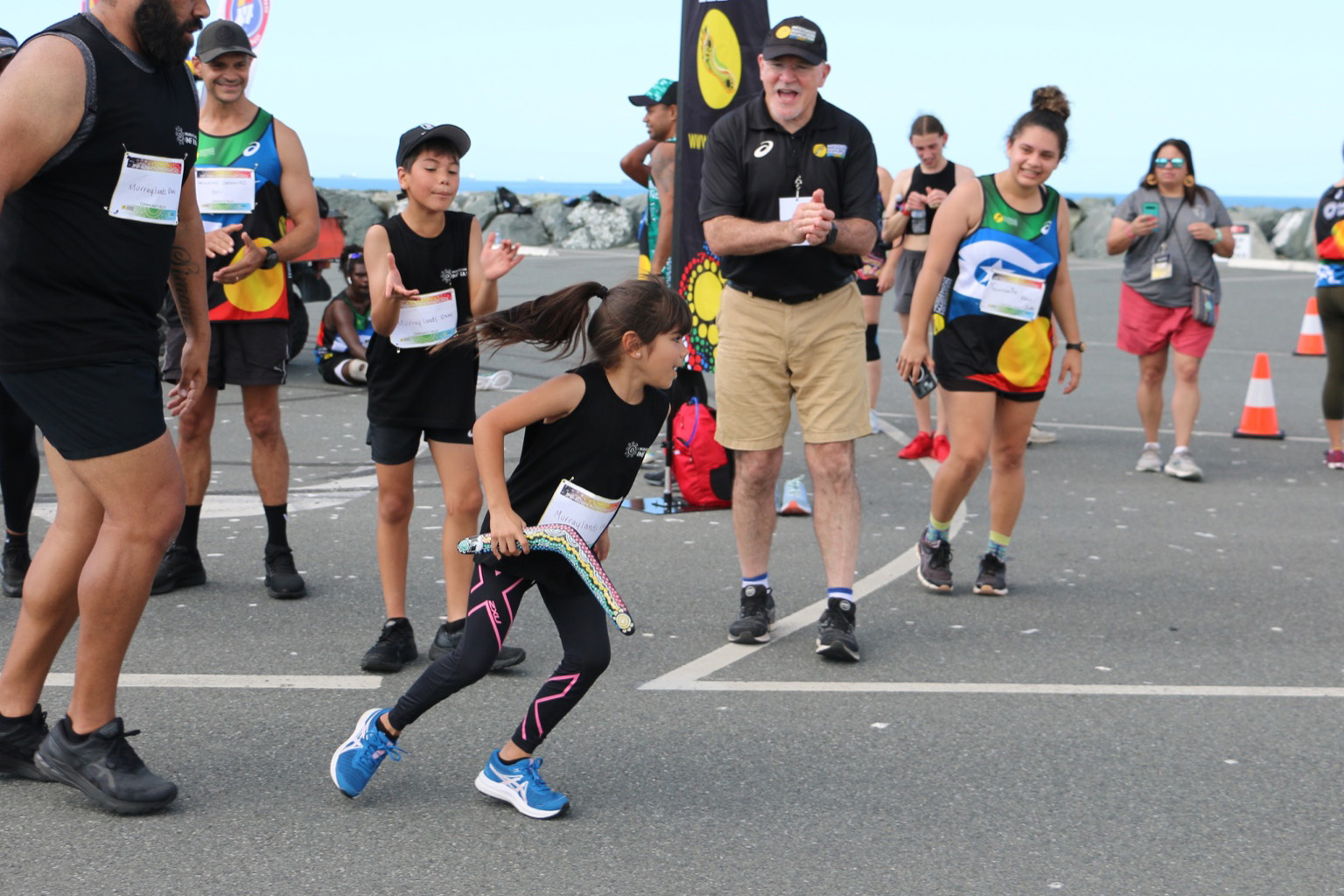 A girl runs with a boomerang relay baton at an IMF RAW event in Mackay, Queensland.