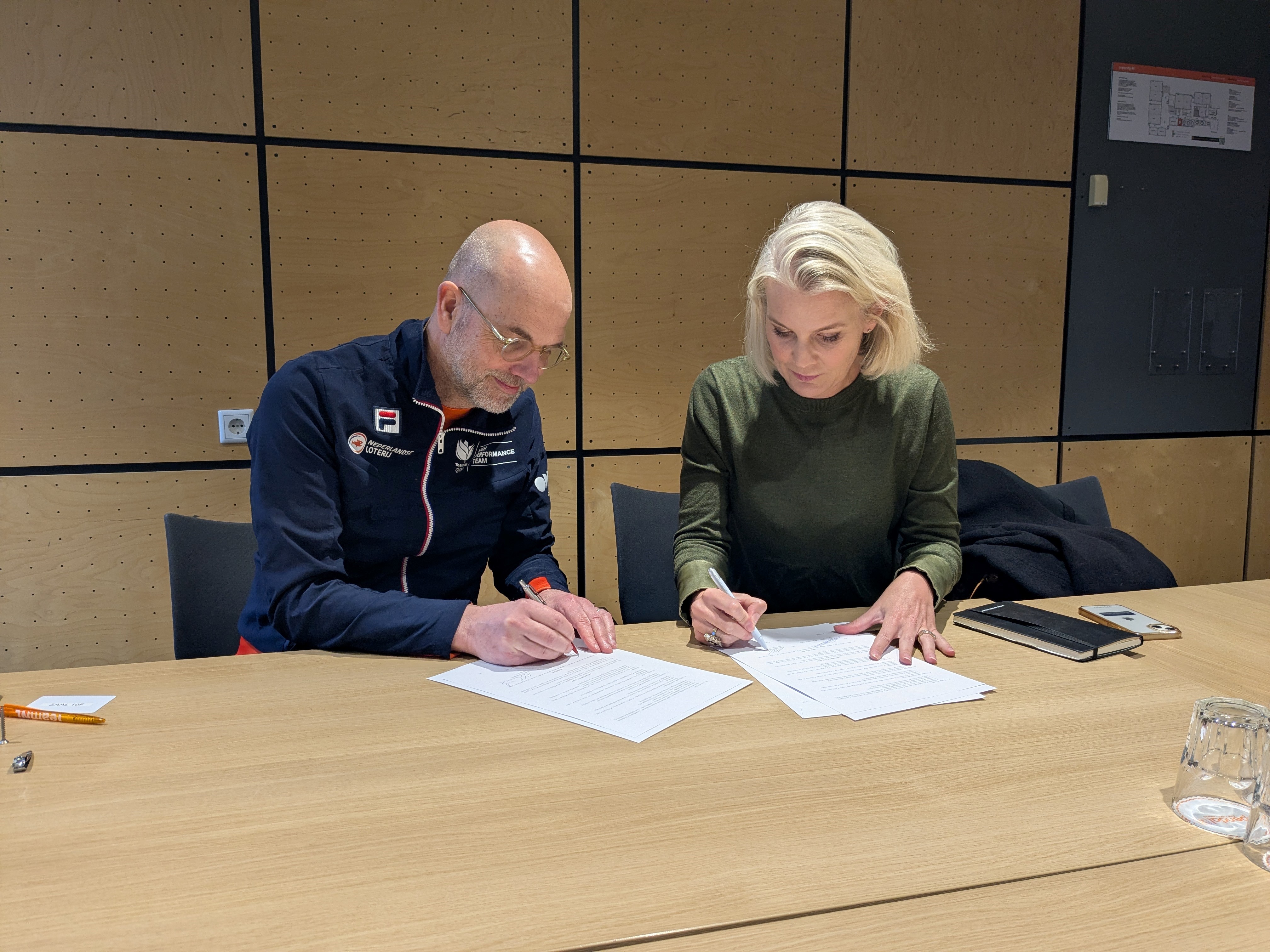two people sign document at table