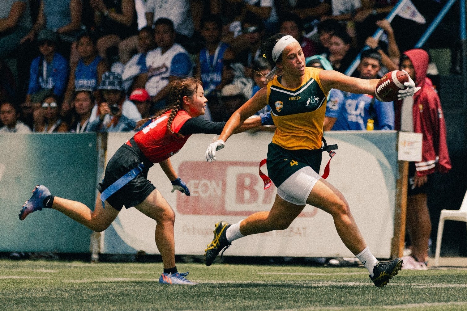 People playing a game of flag football in front of a crowd.