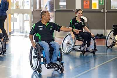 Adult in a wheelchair pointing on an indoor court