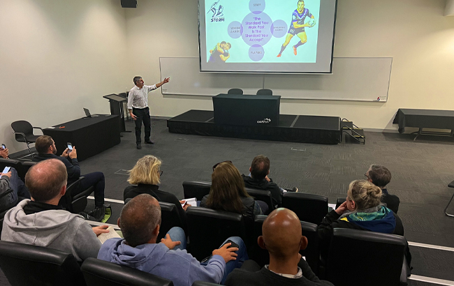 Image of people sitting in a room with a presentation on the screen