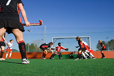 Players compete for the ball during a field hockey match on an outdoor field
