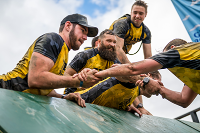A group of veterans helping someone up a wall