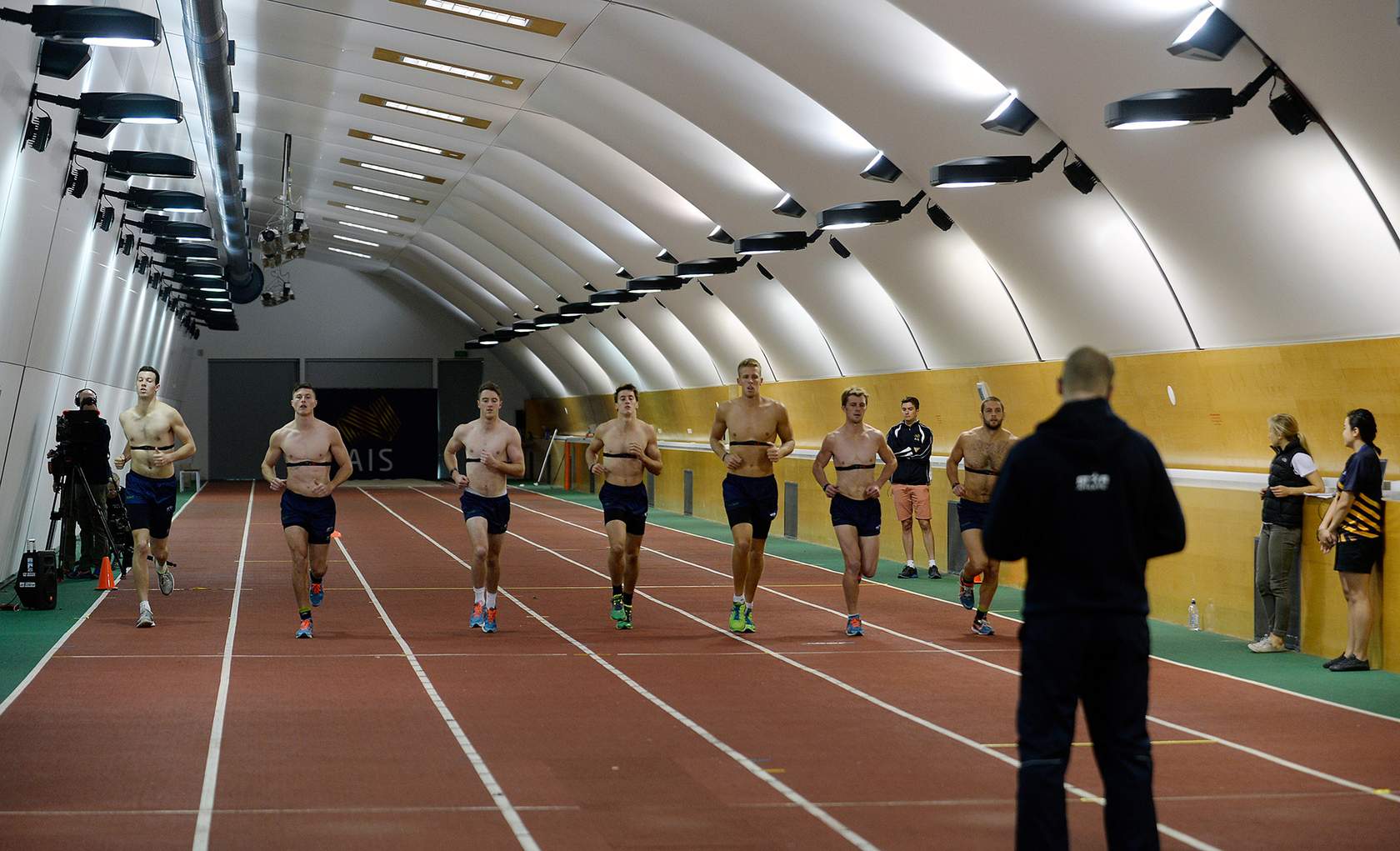 male athletes running beep test on indoor running track