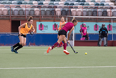 Female hockey player controlling the ball with defenders nearby