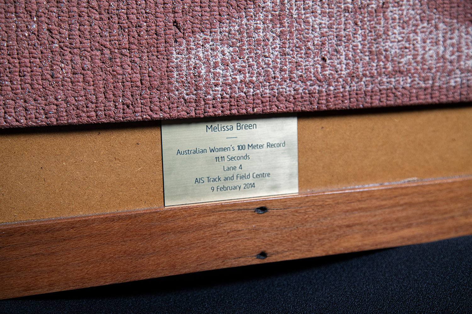 The plaque on the framed piece of AIS track given to Melissa Breen, reading "Melissa Breen - Australian Women's 100 Meter Record 11.11 Seconds Lane 4 AIS Track and Field Centre 9 February 2014".