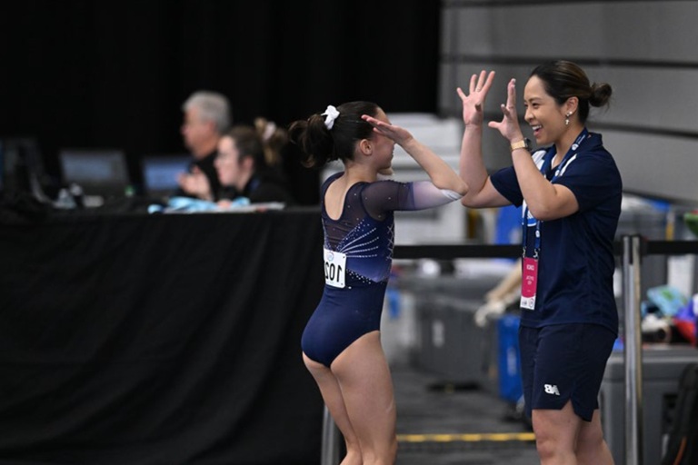 A gymnast and her coach celebrate a successful routine