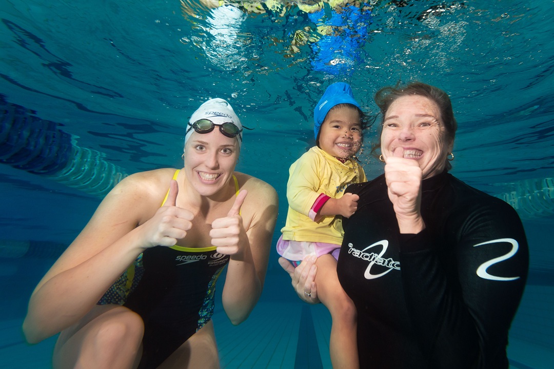 Swim instructor under water with child and parent