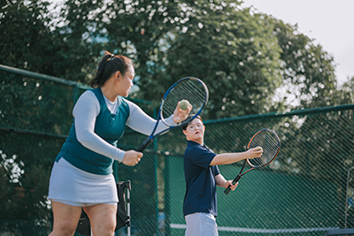 Female tennis trainer coaching a Down syndrome child