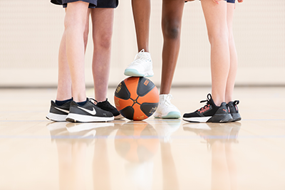 Close up of basketball players legs with one foot on a basketball.