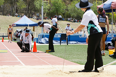 Volunteers measuring a distance in a long jump pit