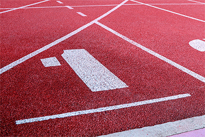 A running track with lane markings painted on a red synthetic surface.