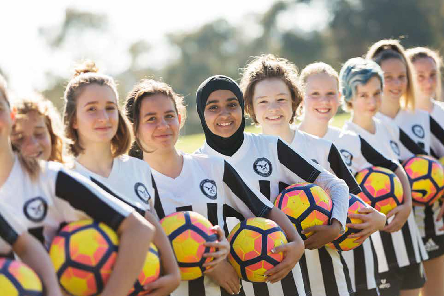 A girls' football team stands together in a line.