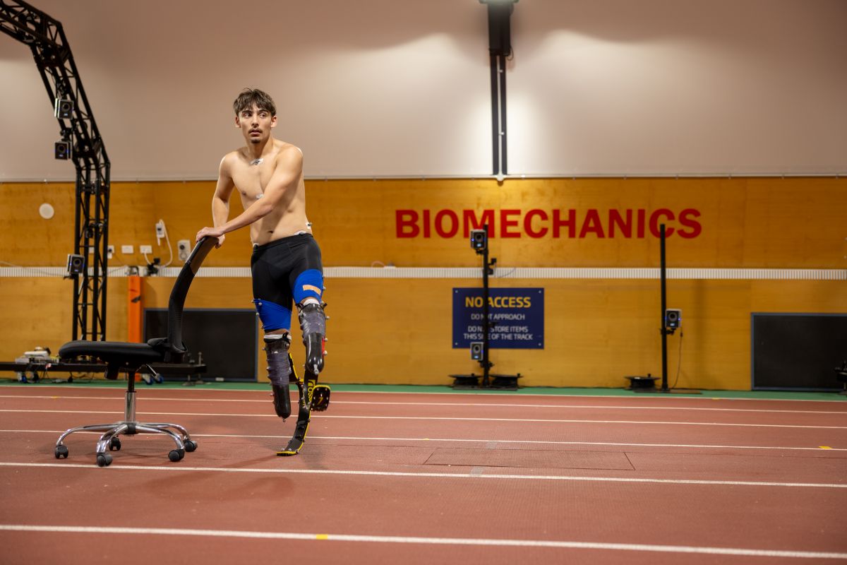 Alex Mijailovic leaning on a chair on the indoor track at the AIS Biomechanics Lab