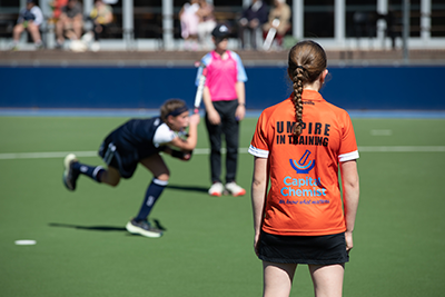 Hockey umpire in training watching the match.