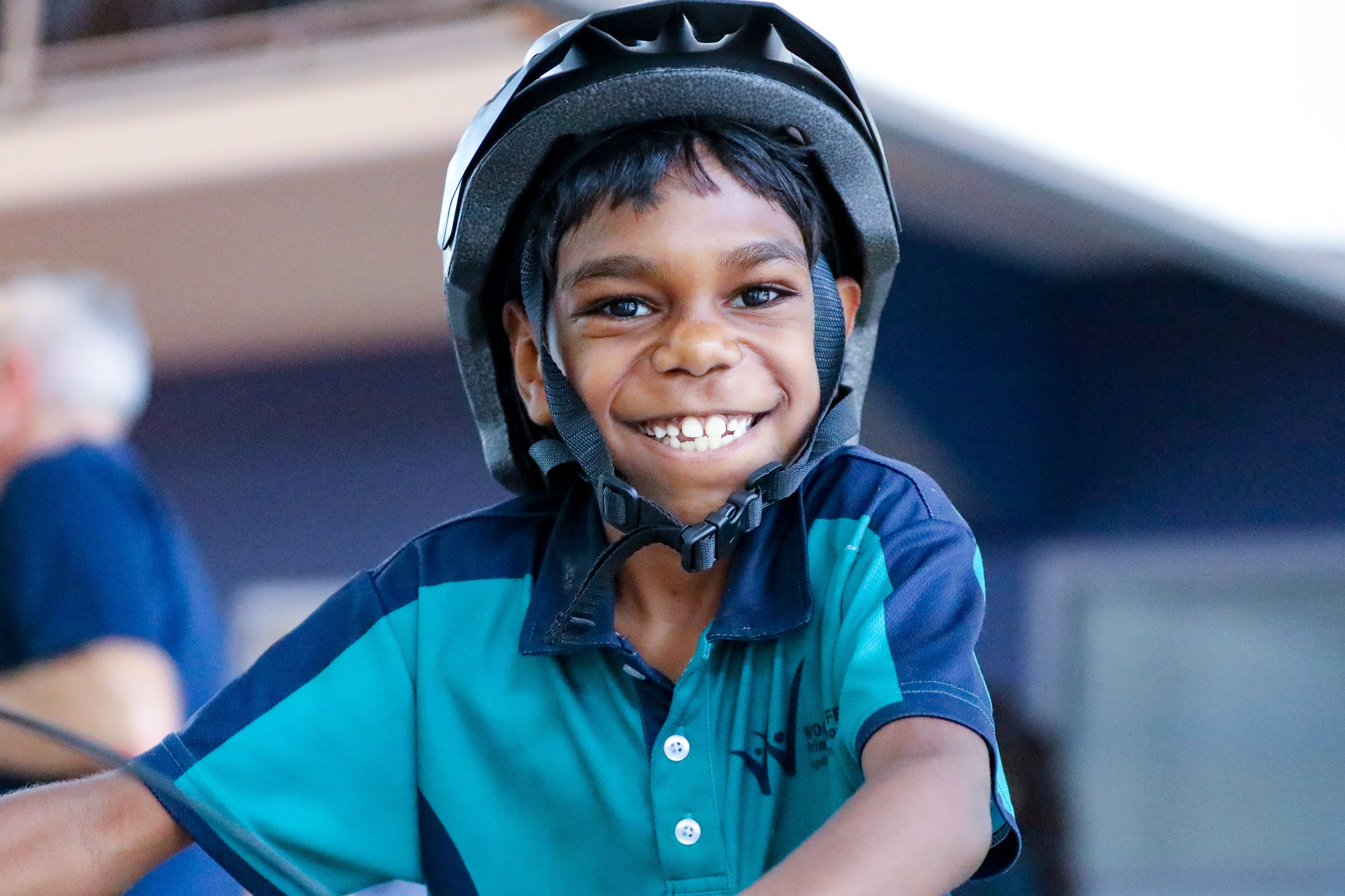 A Frist Nations boy sits on a bike smiling at the camera