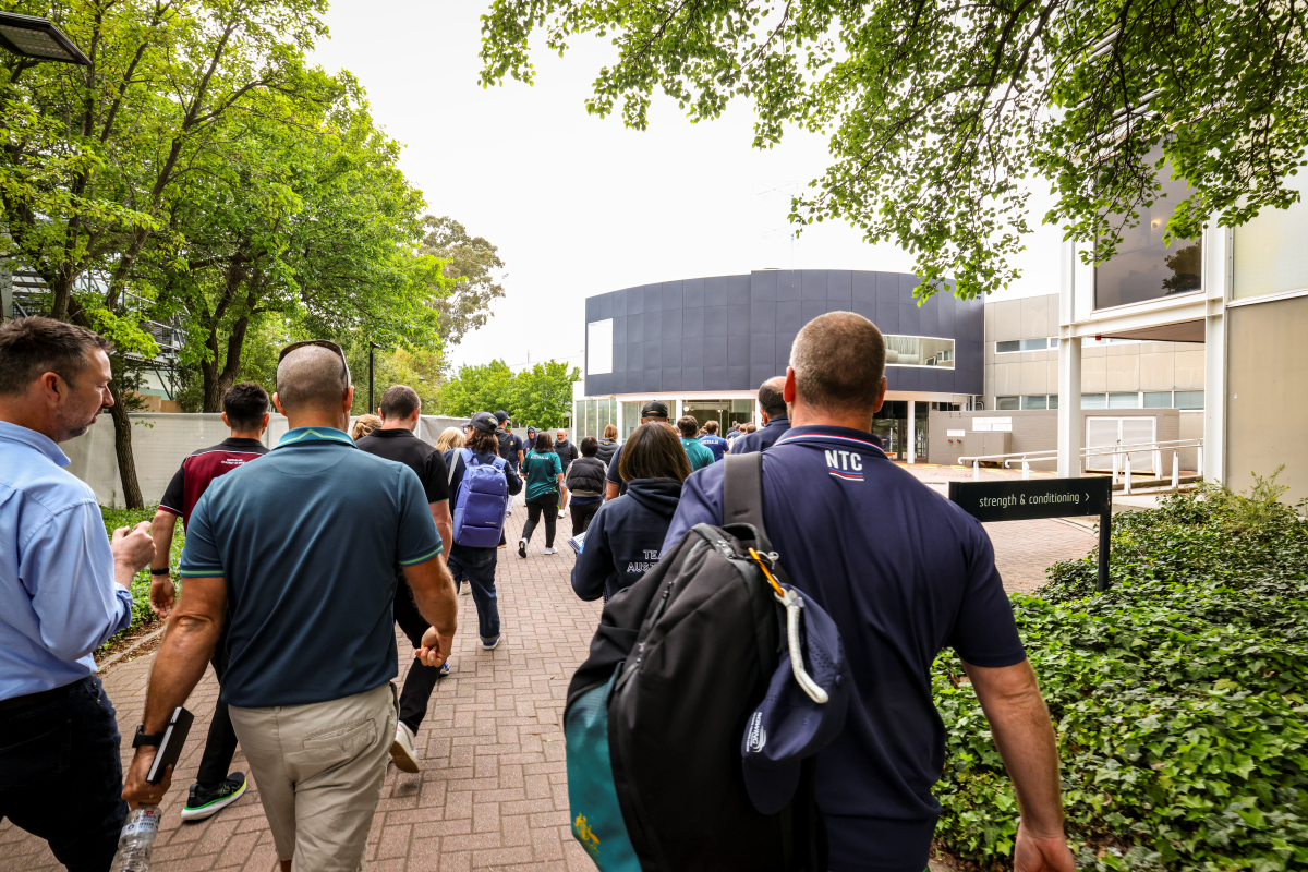 Group of coaches walking towards a building at the AIS.