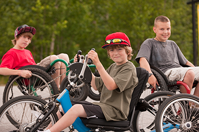 Young boys sitting in wheelchairs and a hand cycles