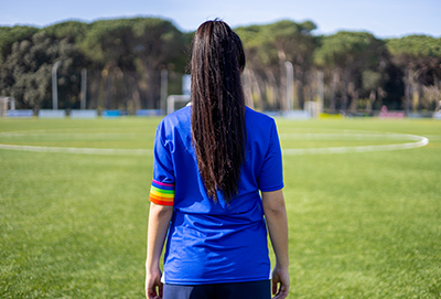 C4S-image-Female with a captain armband with the LGBT pride flag on a football field.