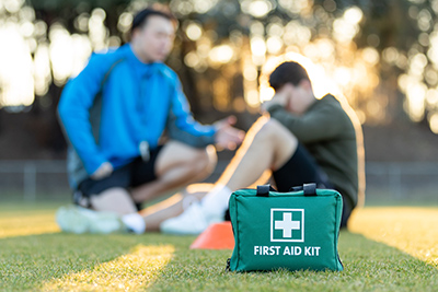 First aid kit in the foreground with a player sitting on the ground in the background