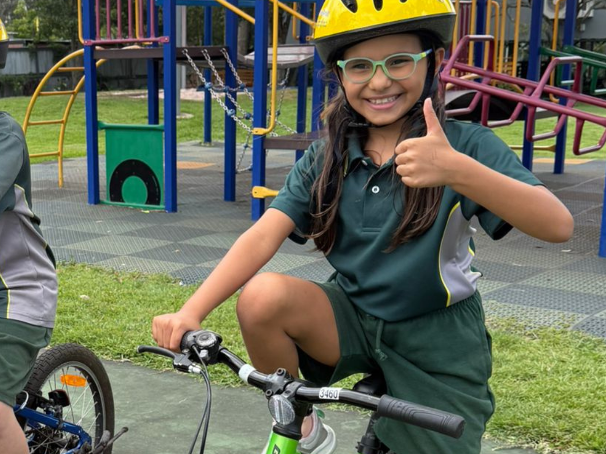 a girl riding a bike and smiling at her school